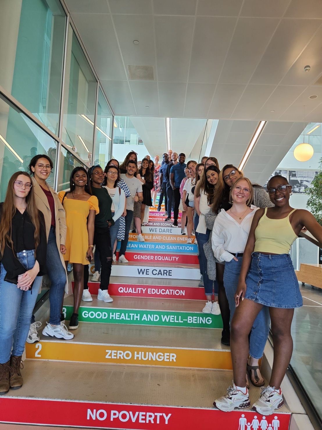 Students standing together next to the staircase decorated with UN sustainable development goals