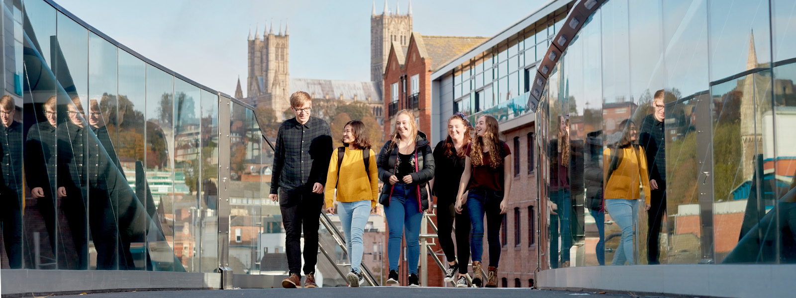 Group of students walking over a bridge with the cathedral in the background